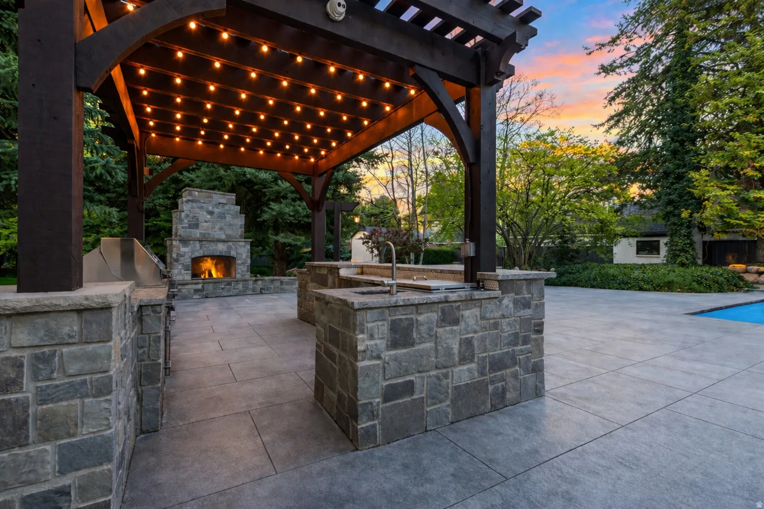 Lighted outdoor kitchen gazebo with lg area for grilling, an outdoor stone fireplace, top of the line appliances.