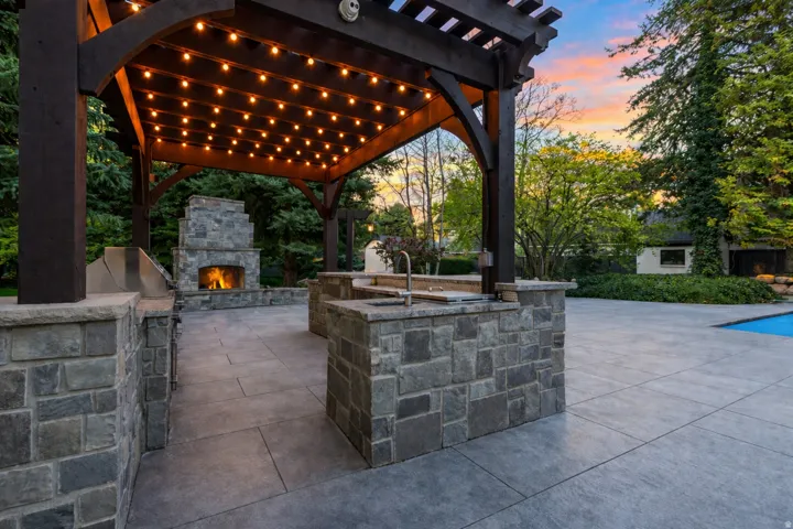 Lighted outdoor kitchen gazebo with lg area for grilling, an outdoor stone fireplace, top of the line appliances.