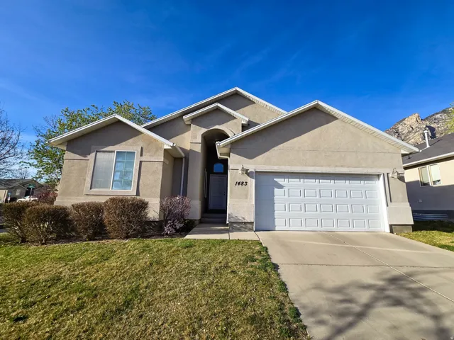 Single story home featuring a garage, concrete driveway, stucco siding, and a front yard