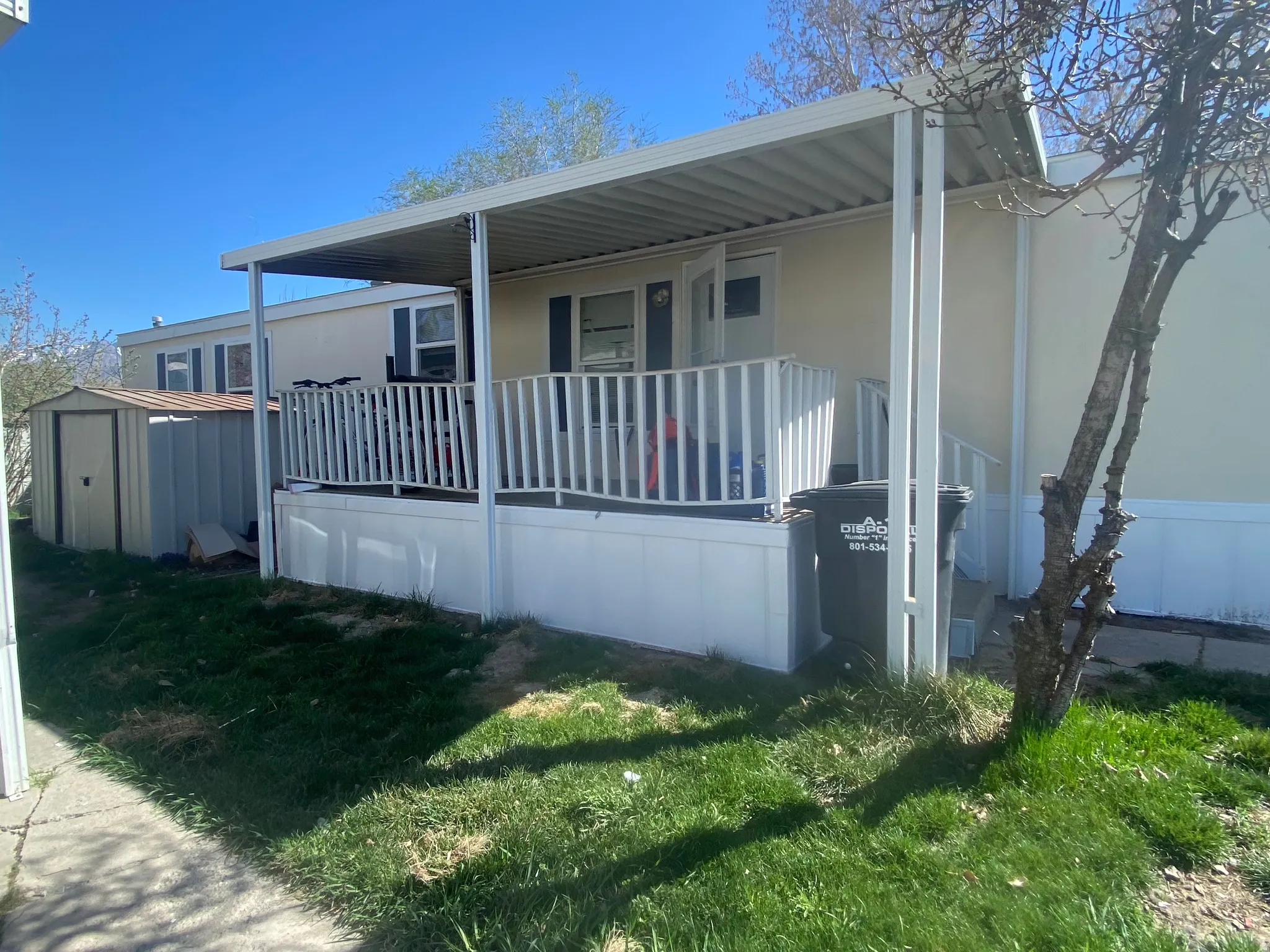 View of side of property featuring a shed, a yard, and covered porch