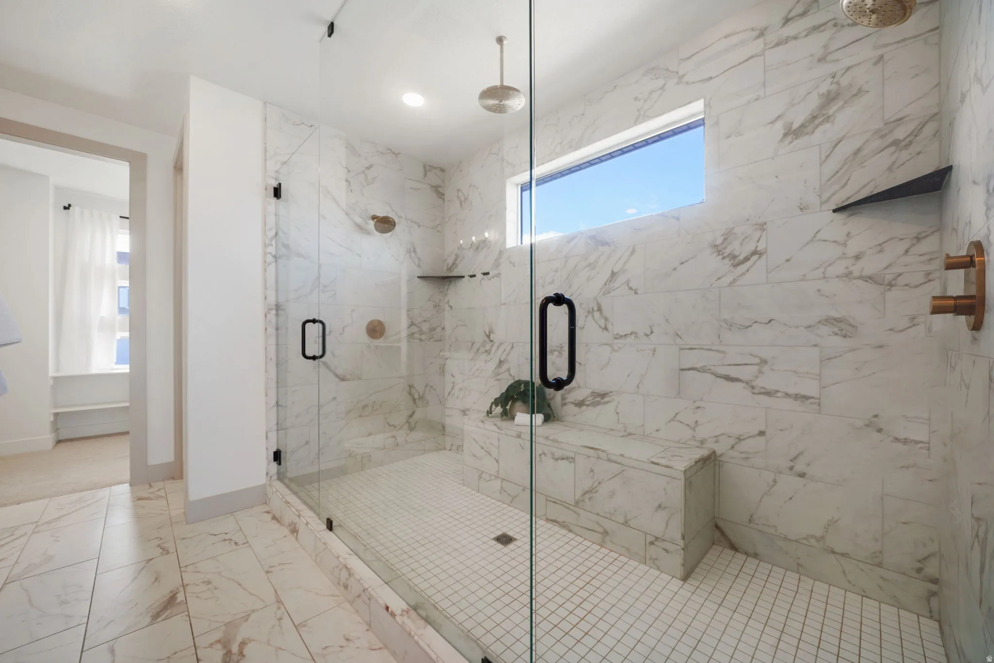 Bathroom featuring light marble finish flooring and a marble finish shower