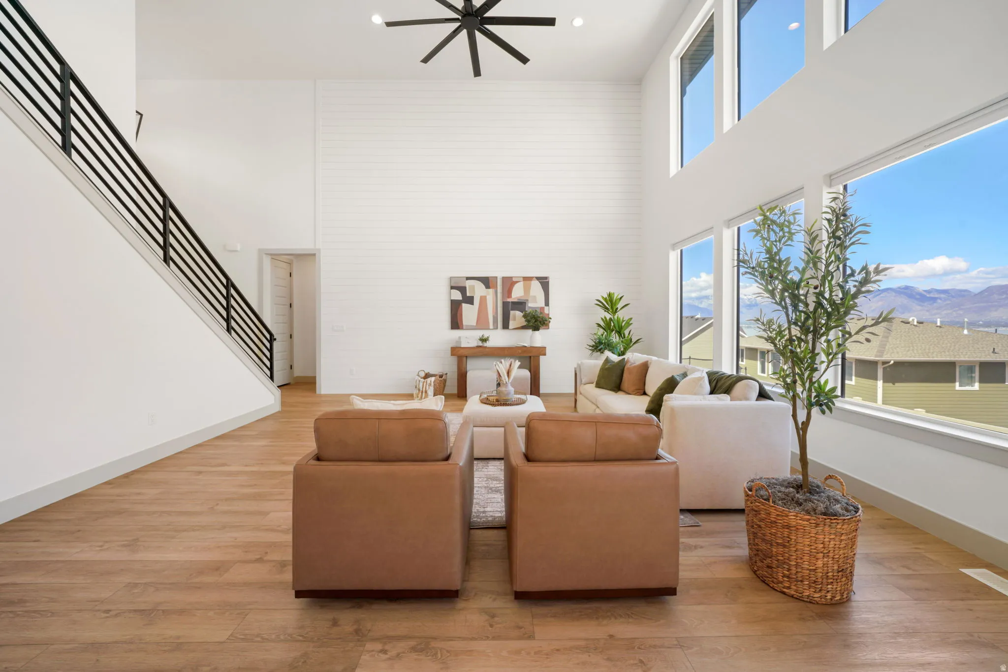 Living room featuring a high ceiling, light wood-style floors, a mountain view, and a ceiling fan