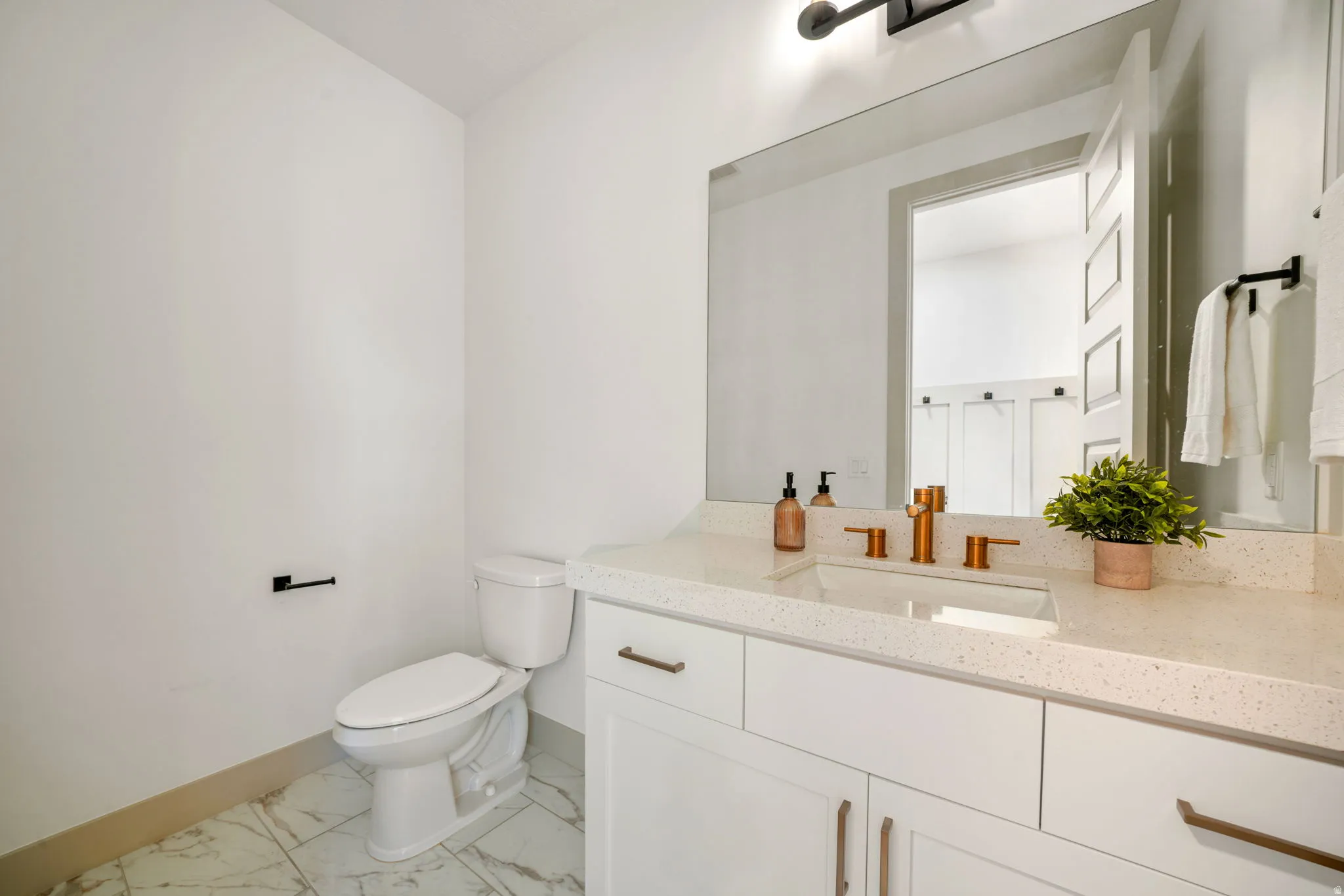 Half bath with vanity and light marble finish flooring