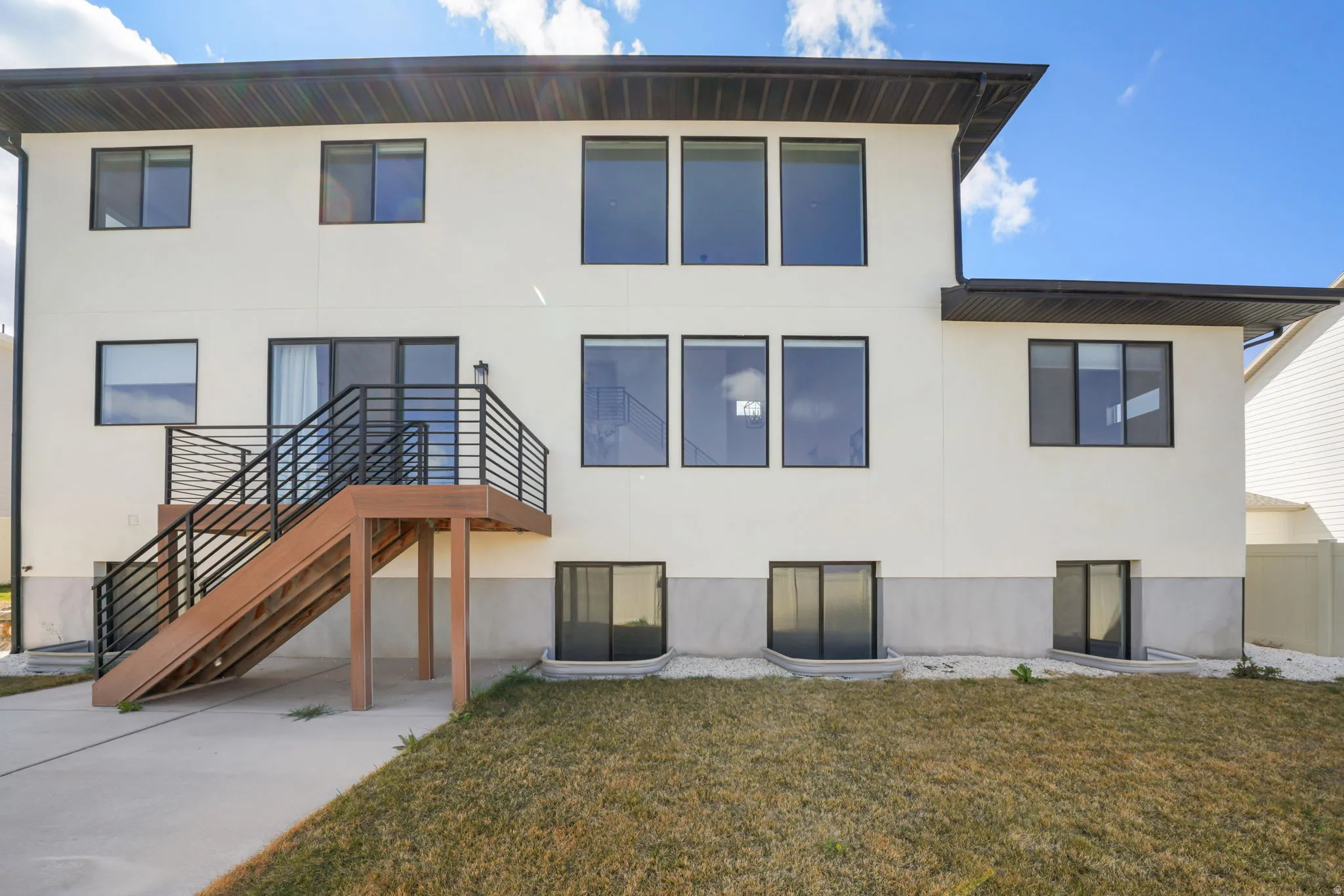 Back of house featuring a lawn and stucco siding