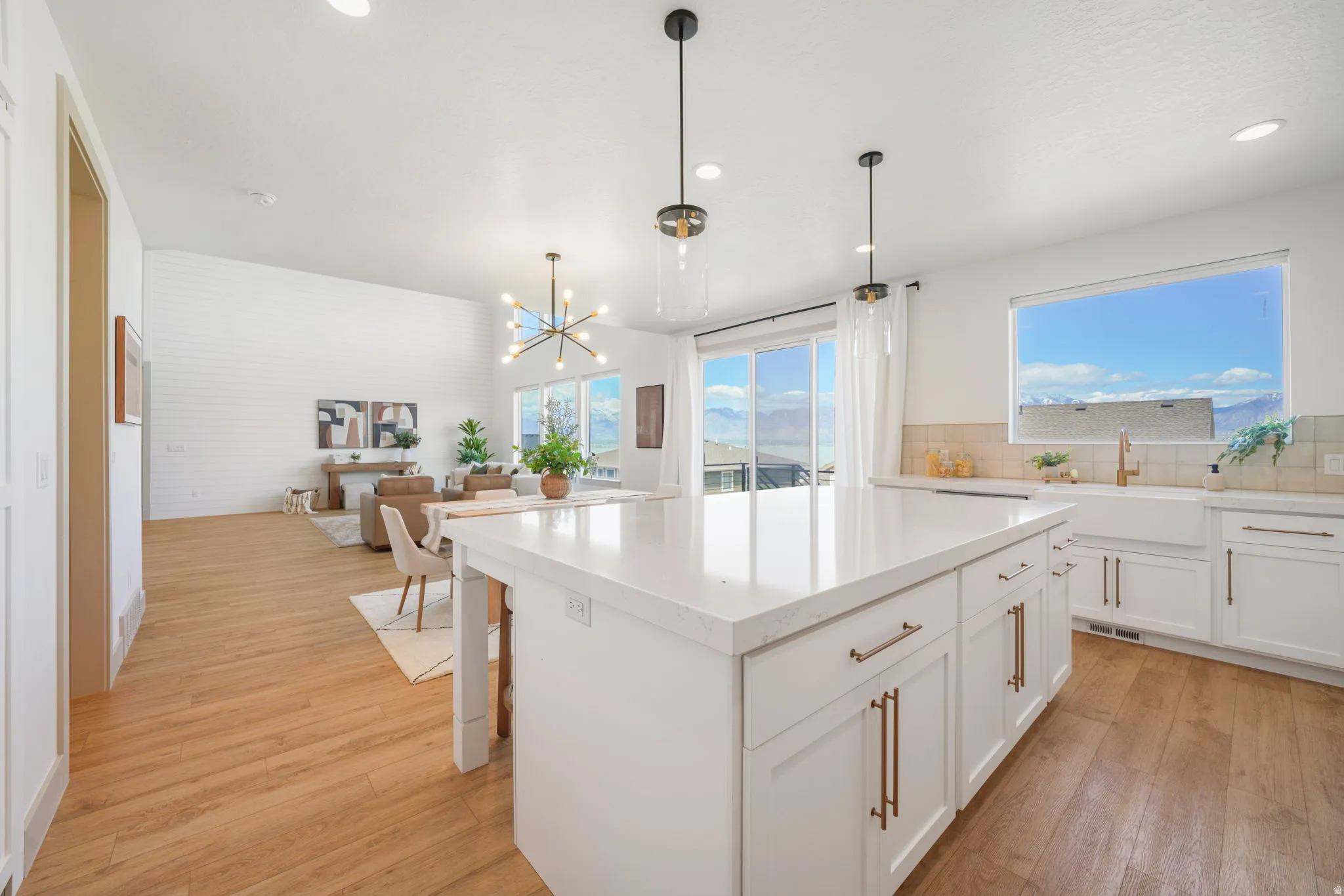 Kitchen with open floor plan, a kitchen island, light wood-style flooring, a chandelier, and white cabinets