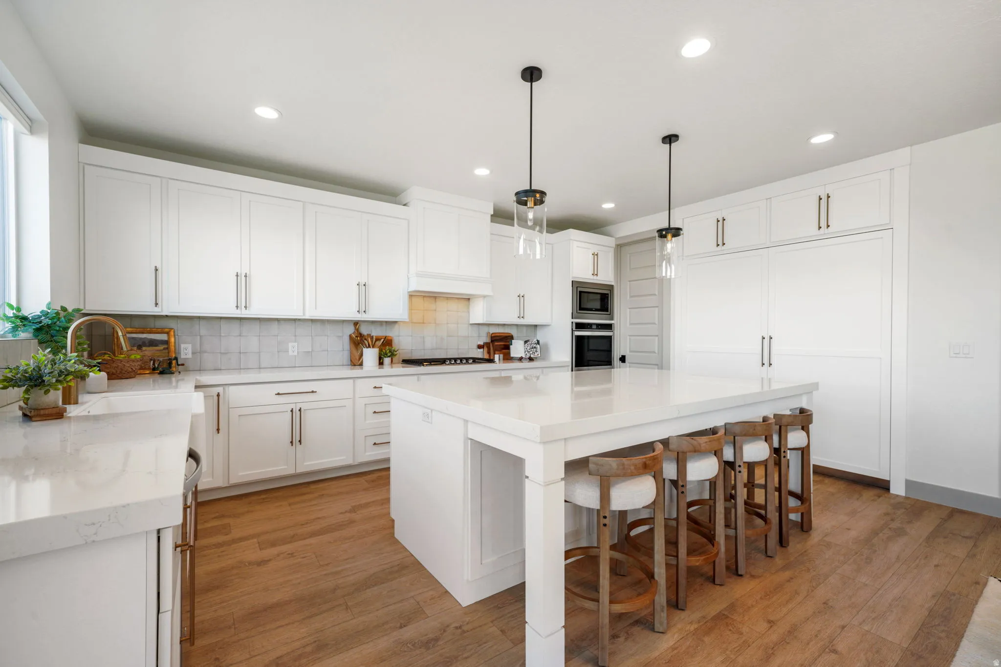 Kitchen with light wood-type flooring, a kitchen breakfast bar, white cabinets, a center island, and decorative light fixtures