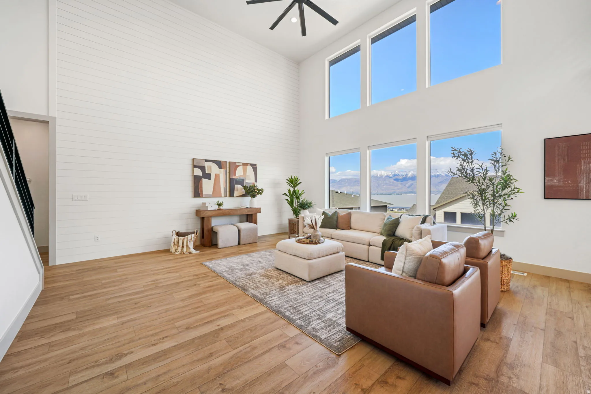 Living area featuring light wood-type flooring, ceiling fan, a high ceiling, and a mountain view