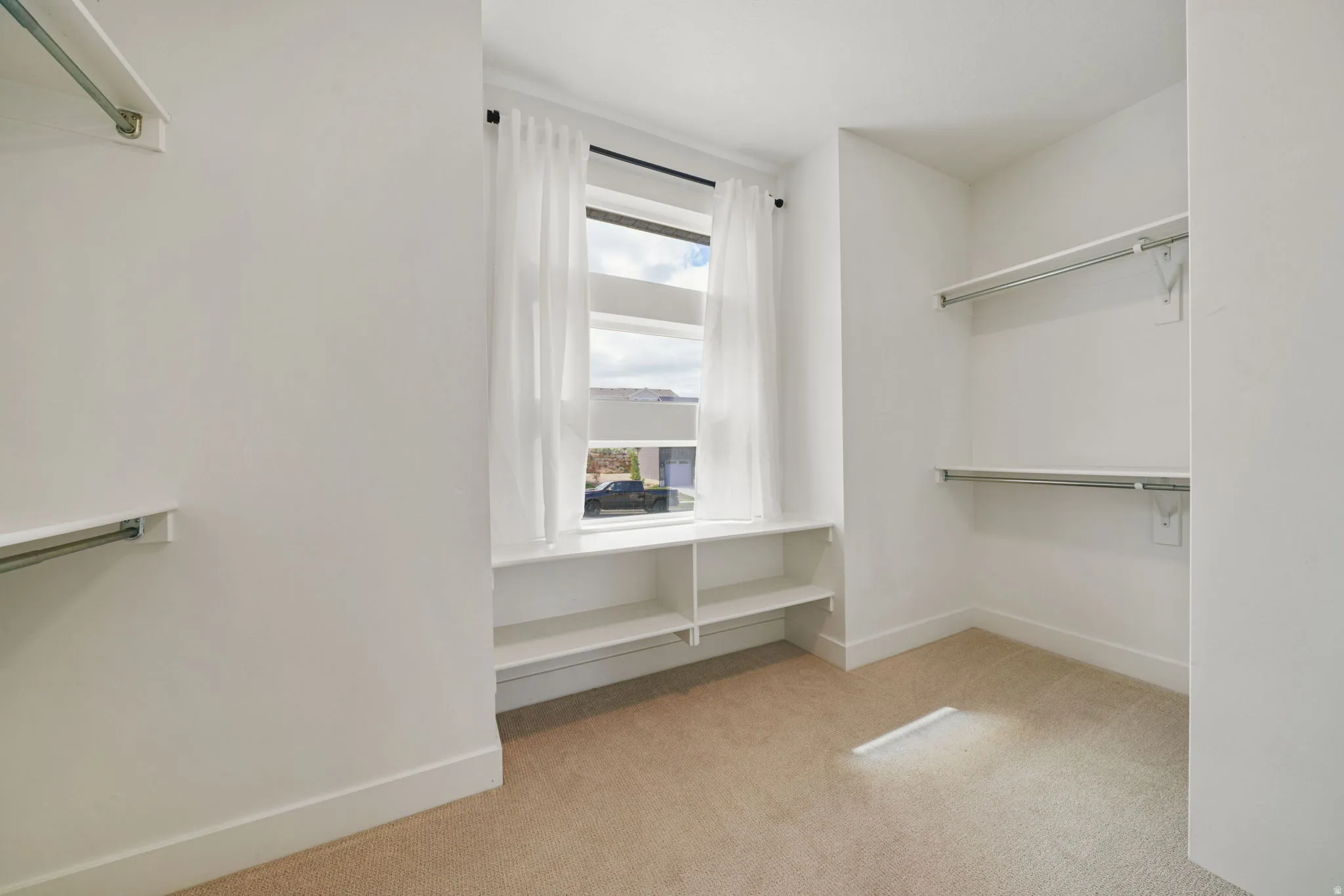Walk in closet featuring light colored carpet