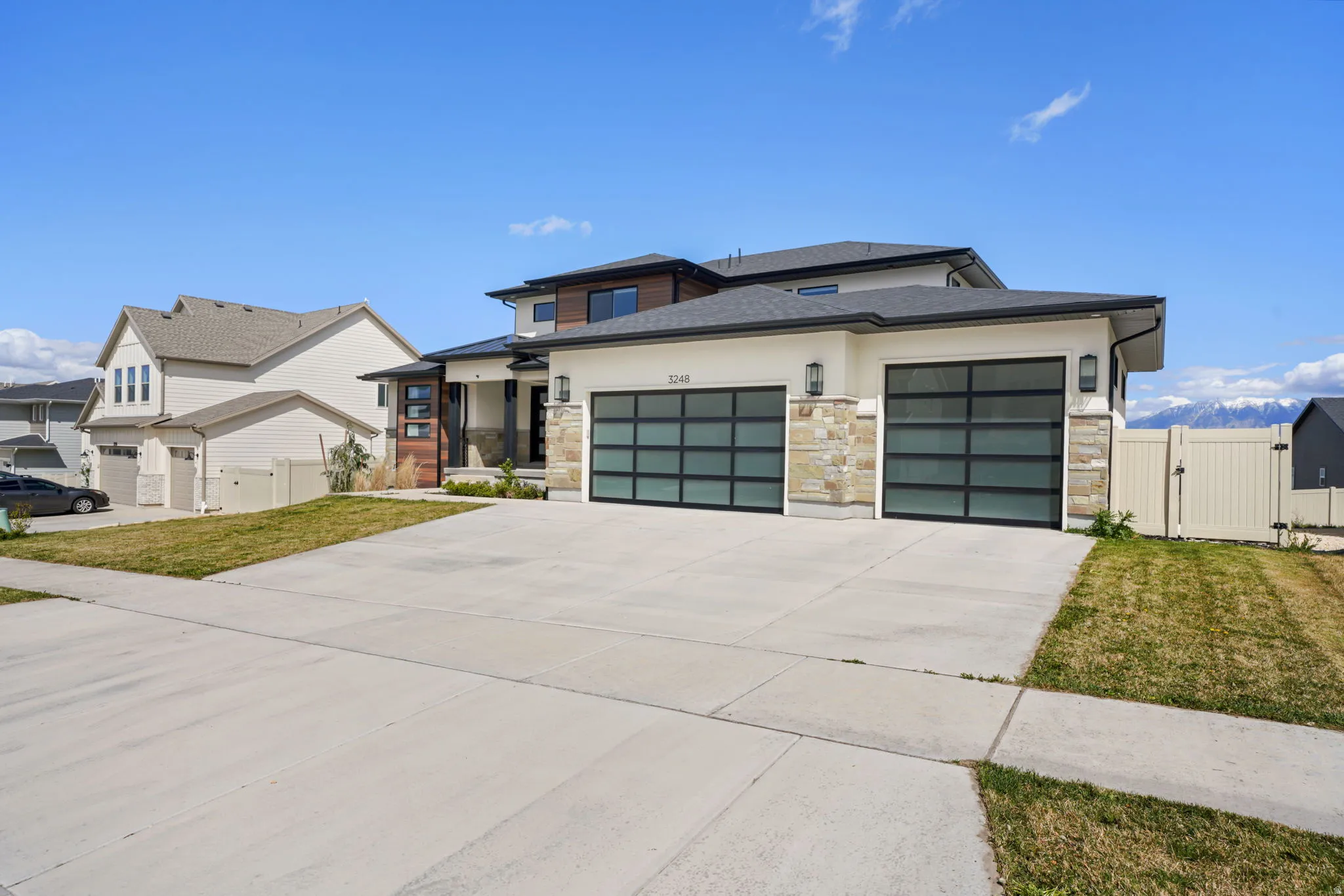 Prairie-style home featuring a gate, an attached garage, concrete driveway, stone siding, and a shingled roof