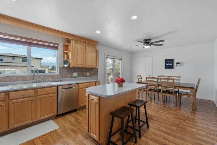 Kitchen with a kitchen island, tasteful backsplash, a ceiling fan, dishwasher, and light wood-style flooring