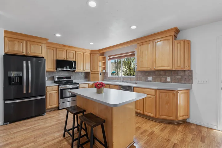Kitchen with stainless steel appliances, light countertops, light wood-style floors, recessed lighting, and a breakfast bar area