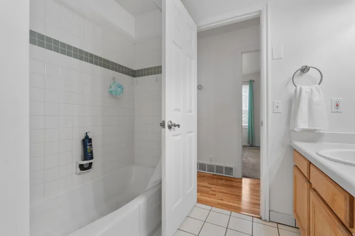 Full bathroom with vanity, light tile patterned floors, and washtub / shower combination
