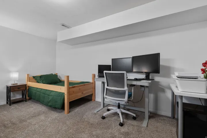 Bedroom with light carpet and an office area
