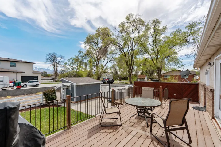 Wooden deck with a lawn, outdoor dining area, a residential view, and a storage shed