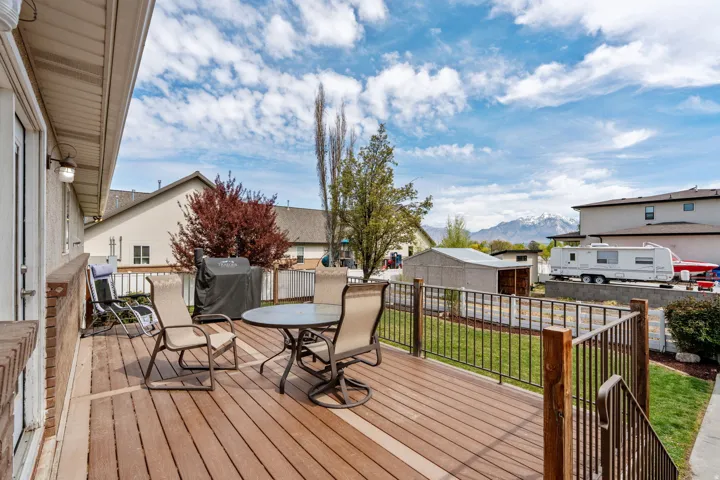 Wooden deck with a residential view, outdoor dining space, grilling area, a mountain view, and a fenced backyard