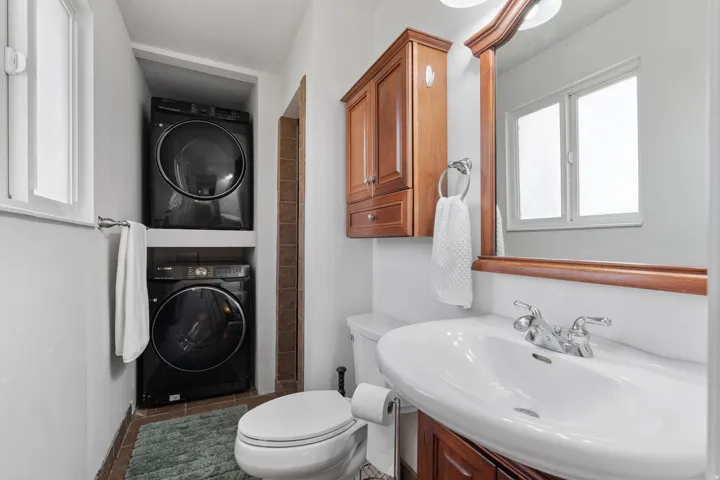 Full bathroom with stacked washer and clothes dryer and vanity