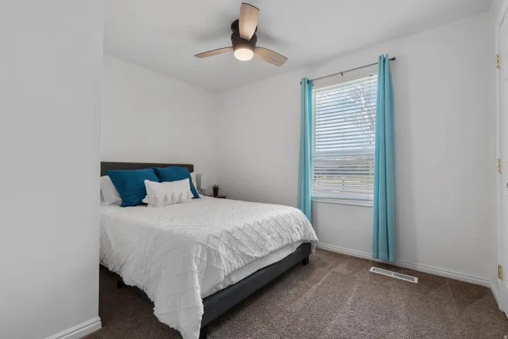 Carpeted bedroom with a ceiling fan and baseboards
