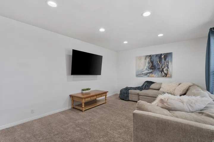 Carpeted living area featuring recessed lighting and baseboards