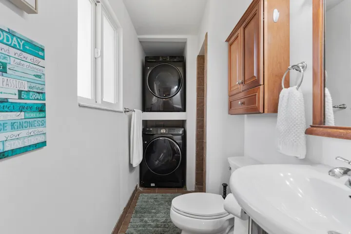Bathroom featuring stacked washer / drying machine and dark tile patterned flooring