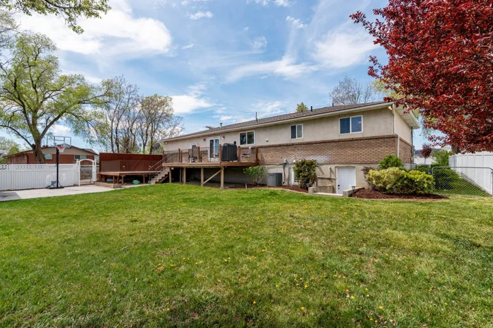 Rear view of property with a fenced backyard, a deck, stucco siding, and brick siding