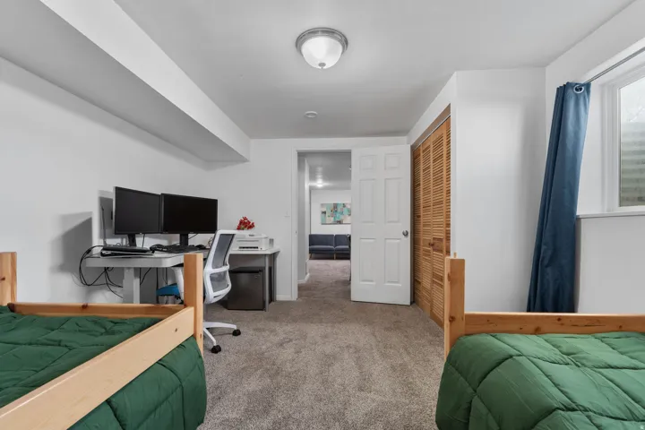 Bedroom featuring an office area, carpet flooring, a closet, and freestanding refrigerator