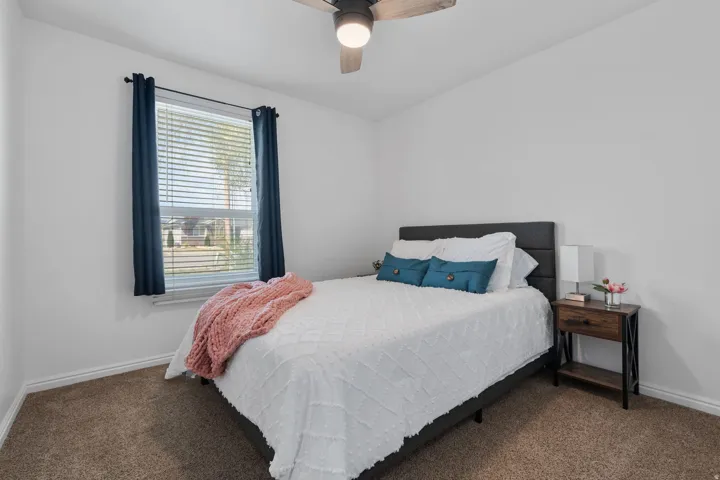 Bedroom with ceiling fan and dark carpet