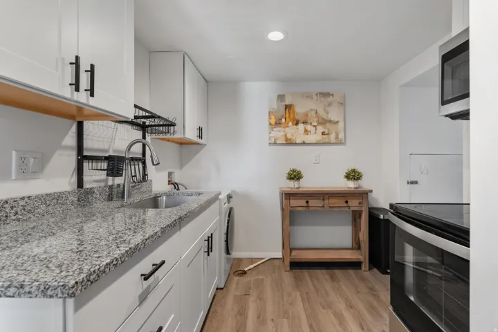 Kitchen featuring light stone countertops, white cabinetry, stainless steel appliances, light wood finished floors, and recessed lighting