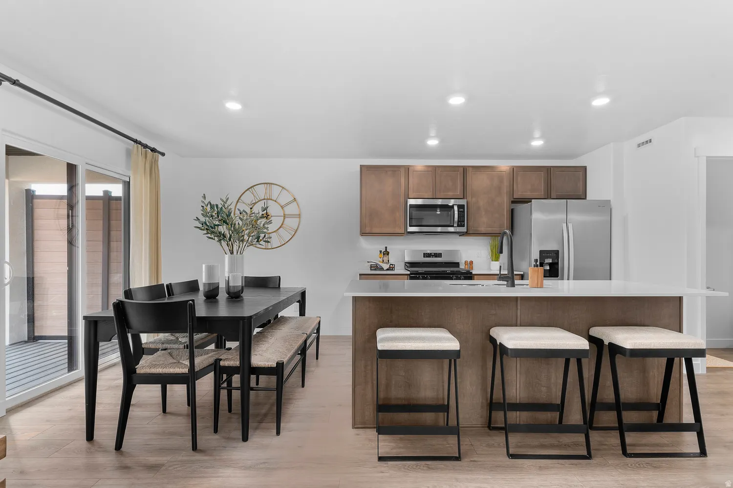 Kitchen featuring a kitchen island with sink, stainless steel appliances, a breakfast bar, light wood-type flooring, and recessed lighting