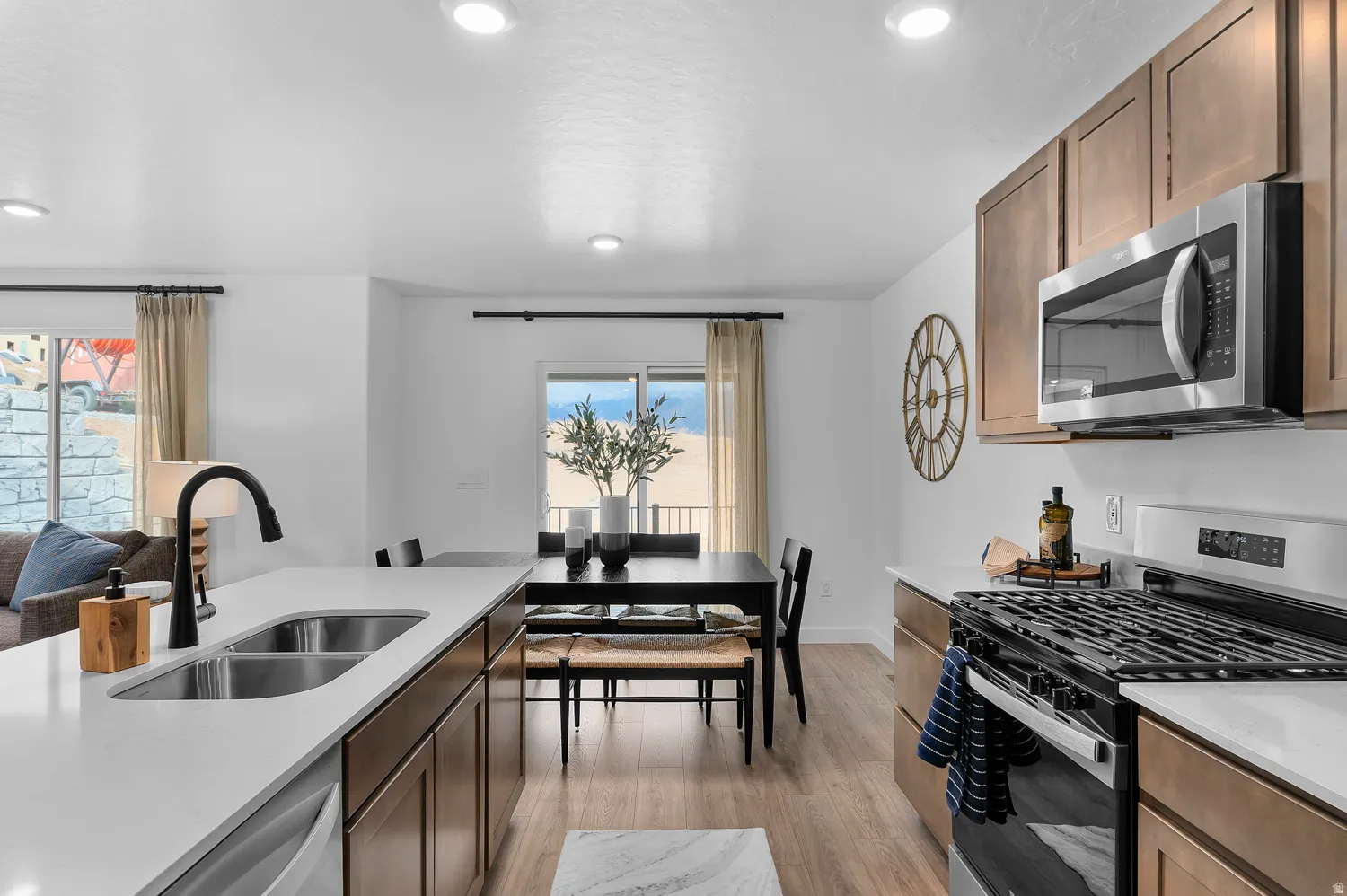 Kitchen with stainless steel appliances, light stone counters, light wood-type flooring, open floor plan, and recessed lighting