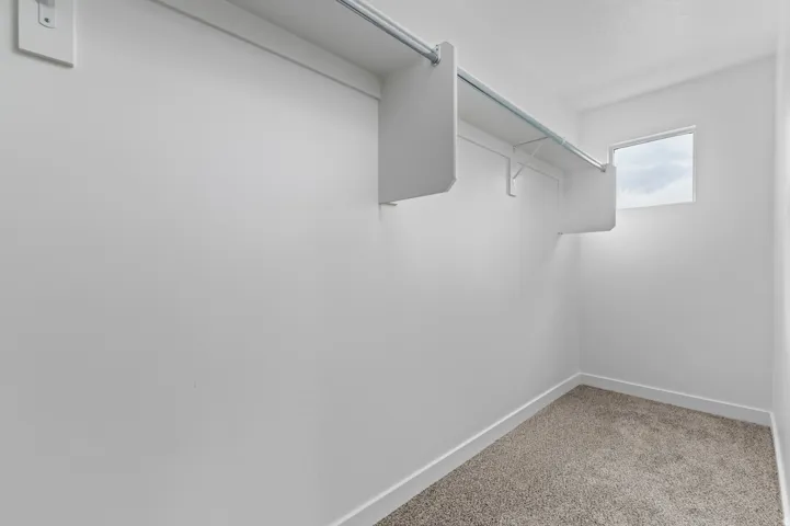 Walk in closet featuring light colored carpet