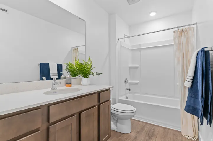 Bathroom with vanity, light wood-style floors, and shower / bathtub combination with curtain
