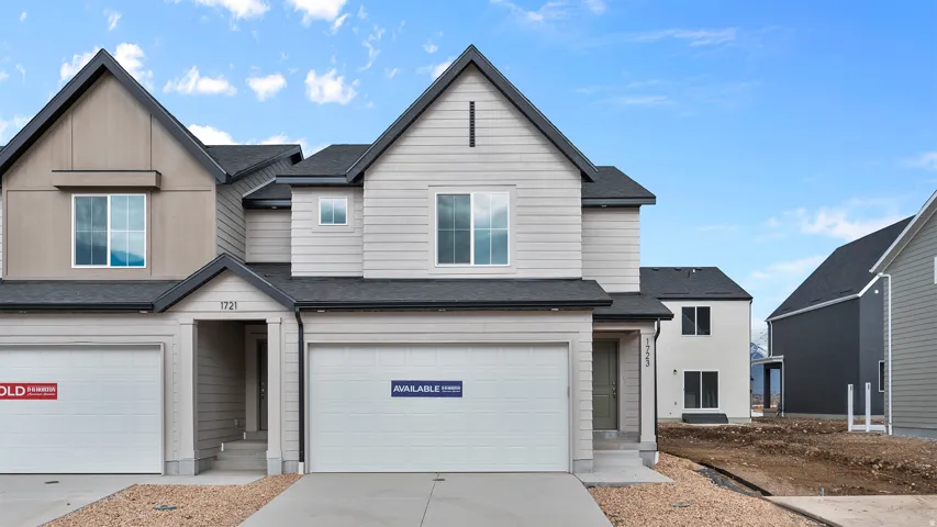 View of front facade featuring an attached garage, a shingled roof, and concrete driveway
