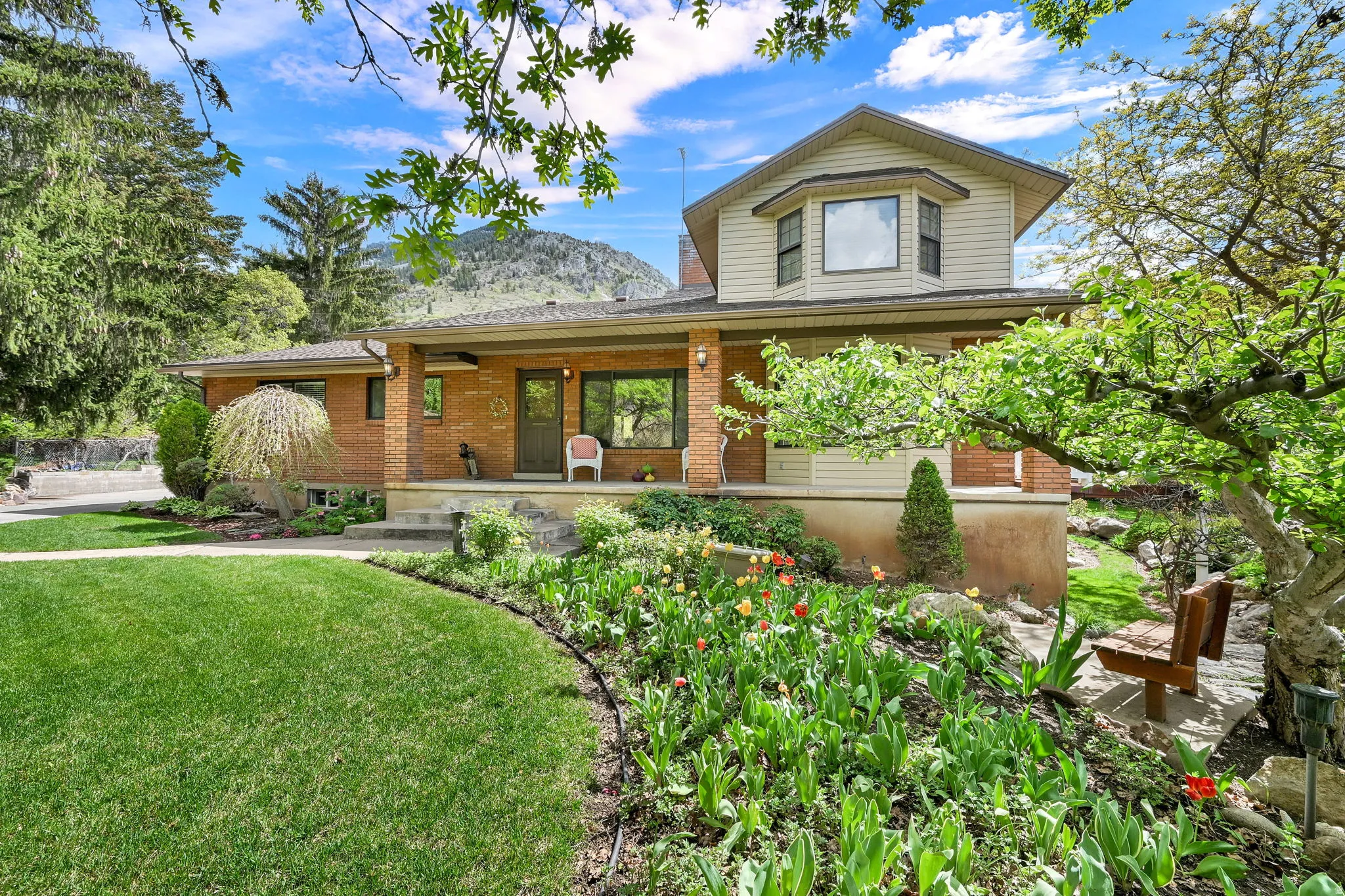 View of front of house featuring covered porch, brick siding, and a front lawn