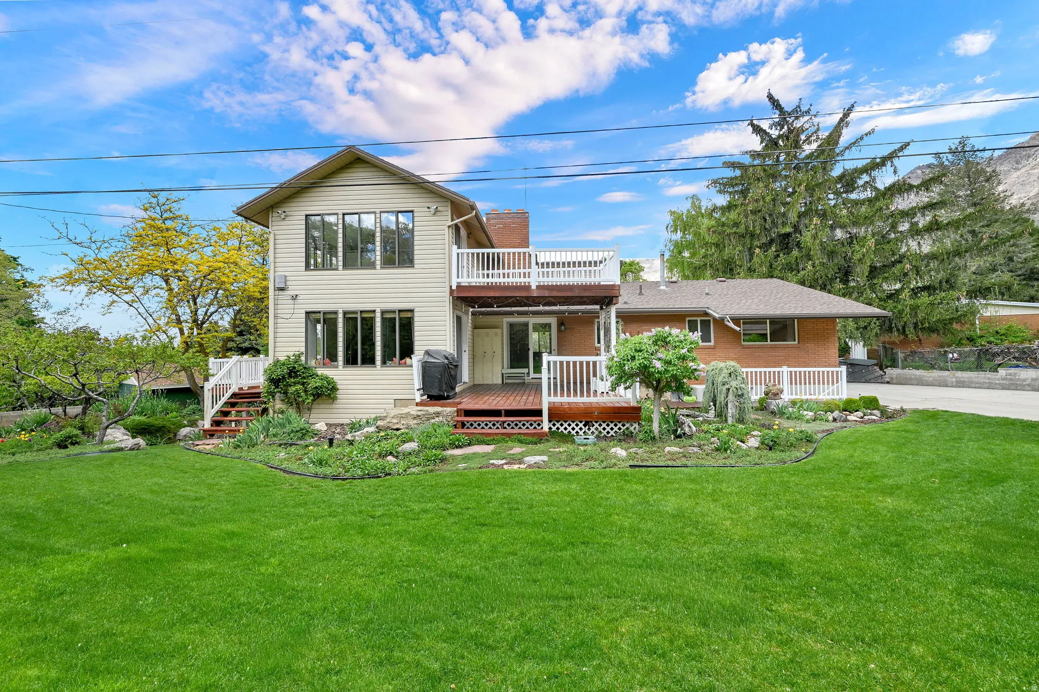 Back of property featuring a wooden deck, a yard, a chimney, and brick siding