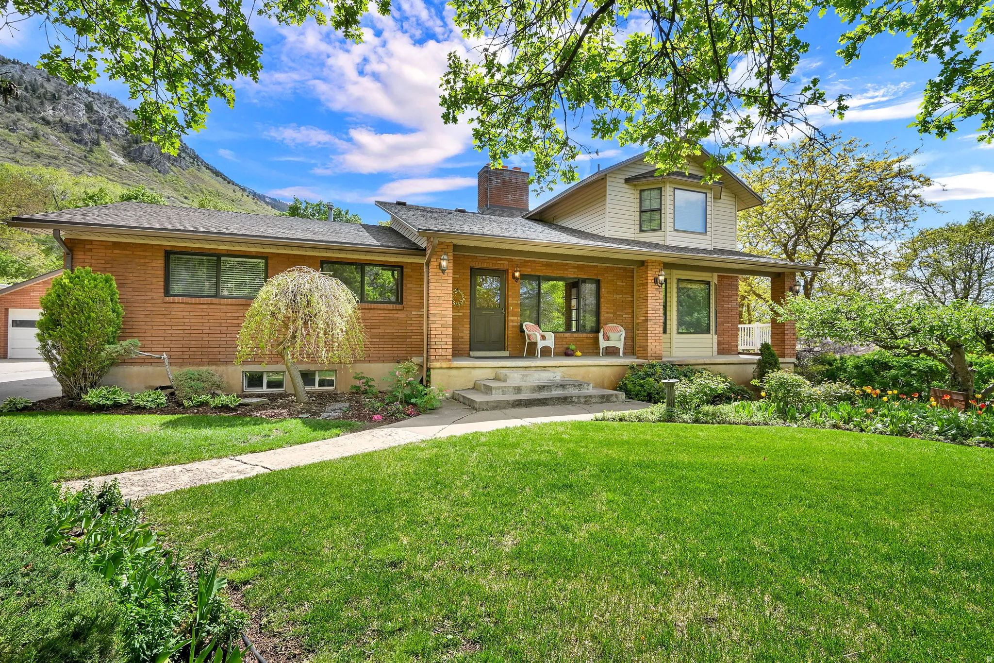 View of front of property with brick siding, a front yard, covered porch, a chimney, and a shingled roof