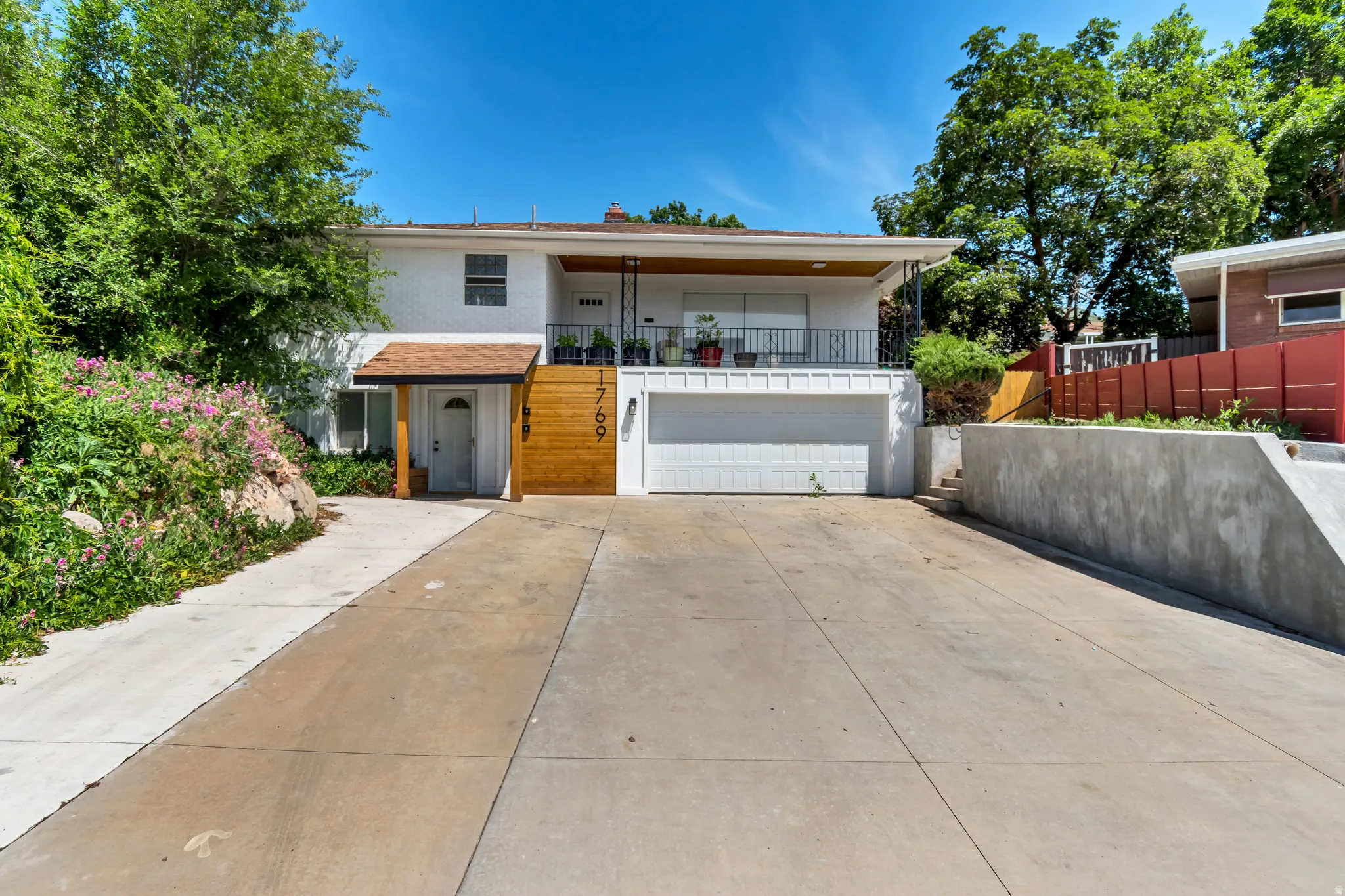 View of front of home with a balcony, concrete driveway, a garage, and stucco siding