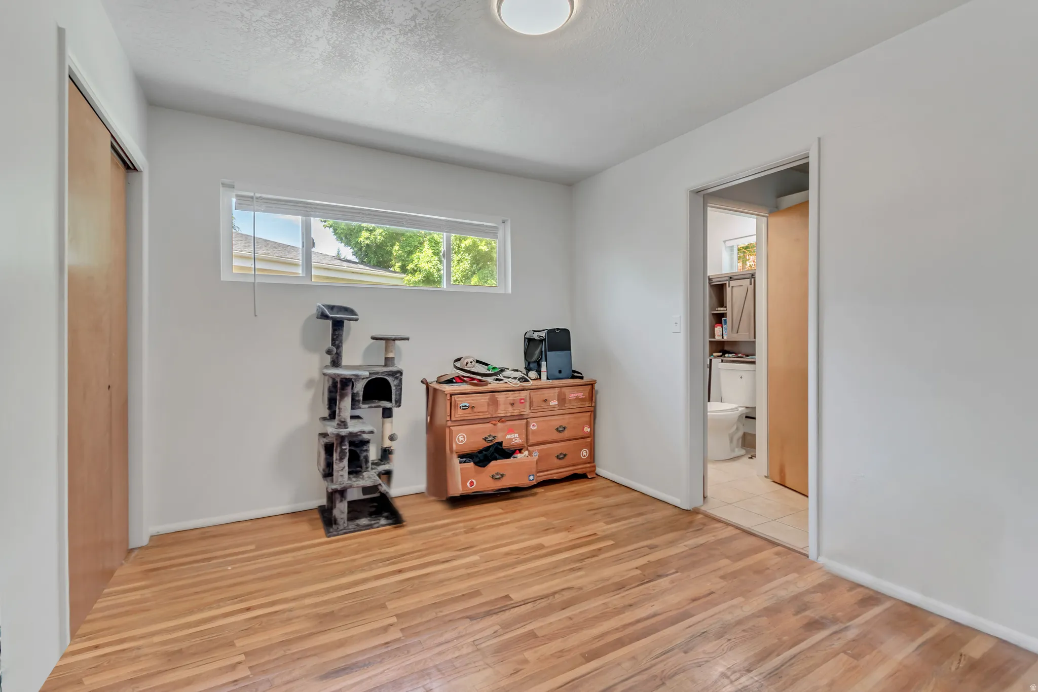 Bedroom featuring light wood-style flooring, a closet, and a textured ceiling