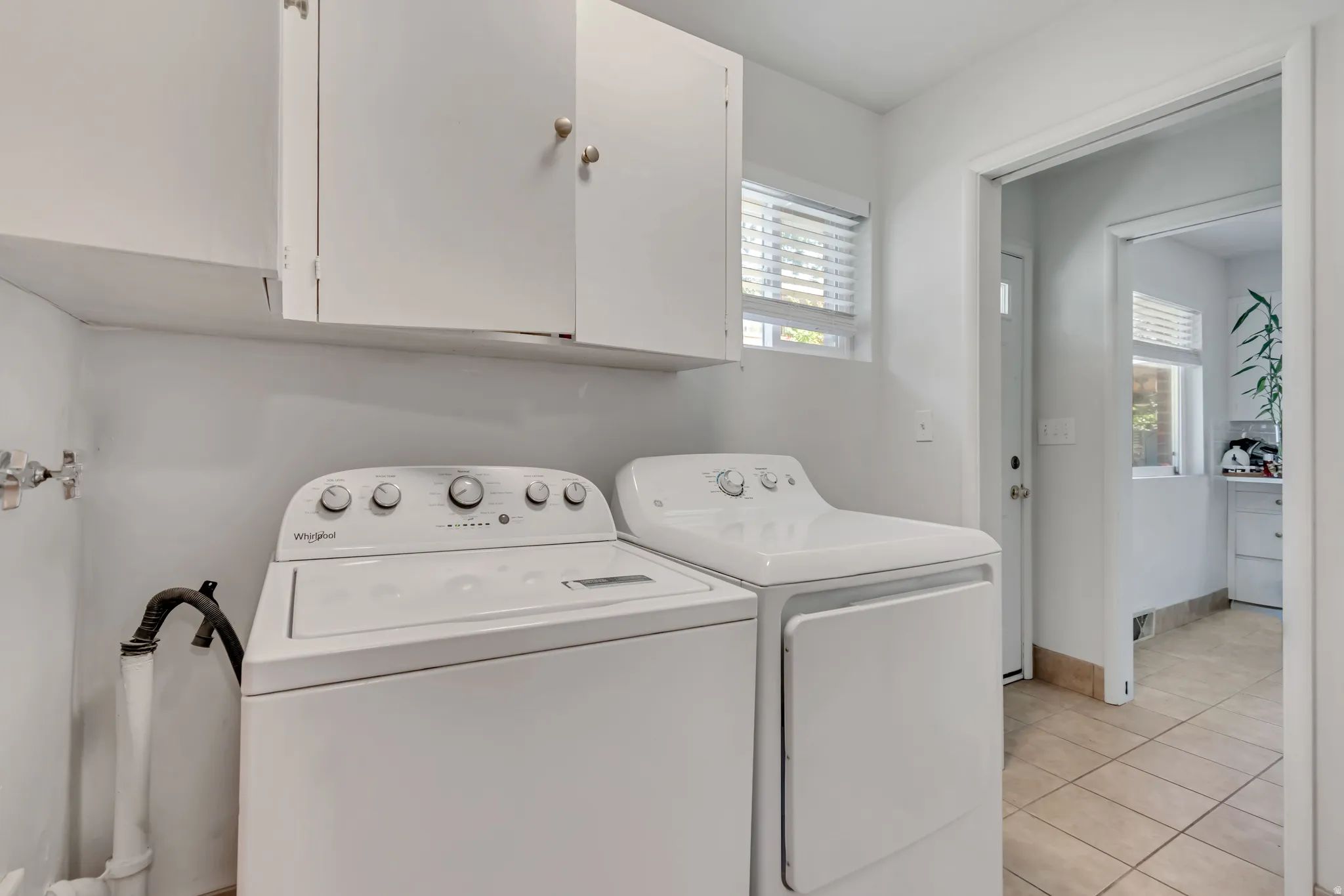 Laundry room featuring washer and clothes dryer, light tile patterned floors, and cabinet space