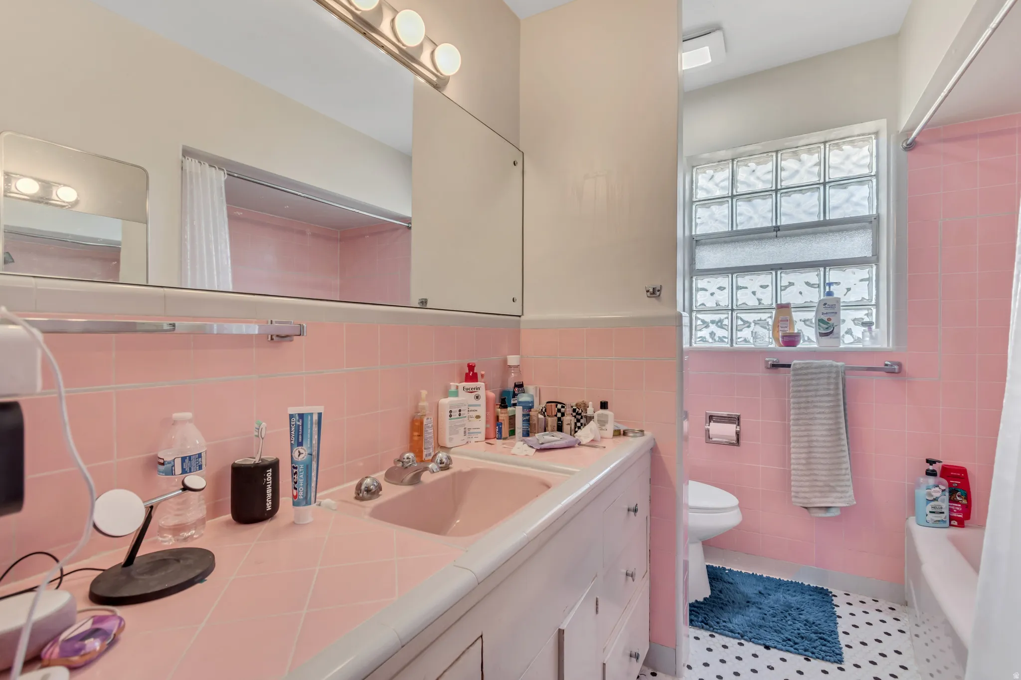 Bathroom with vanity, shower / bath combo with shower curtain, a wainscoted wall, tile walls, and light tile patterned floors