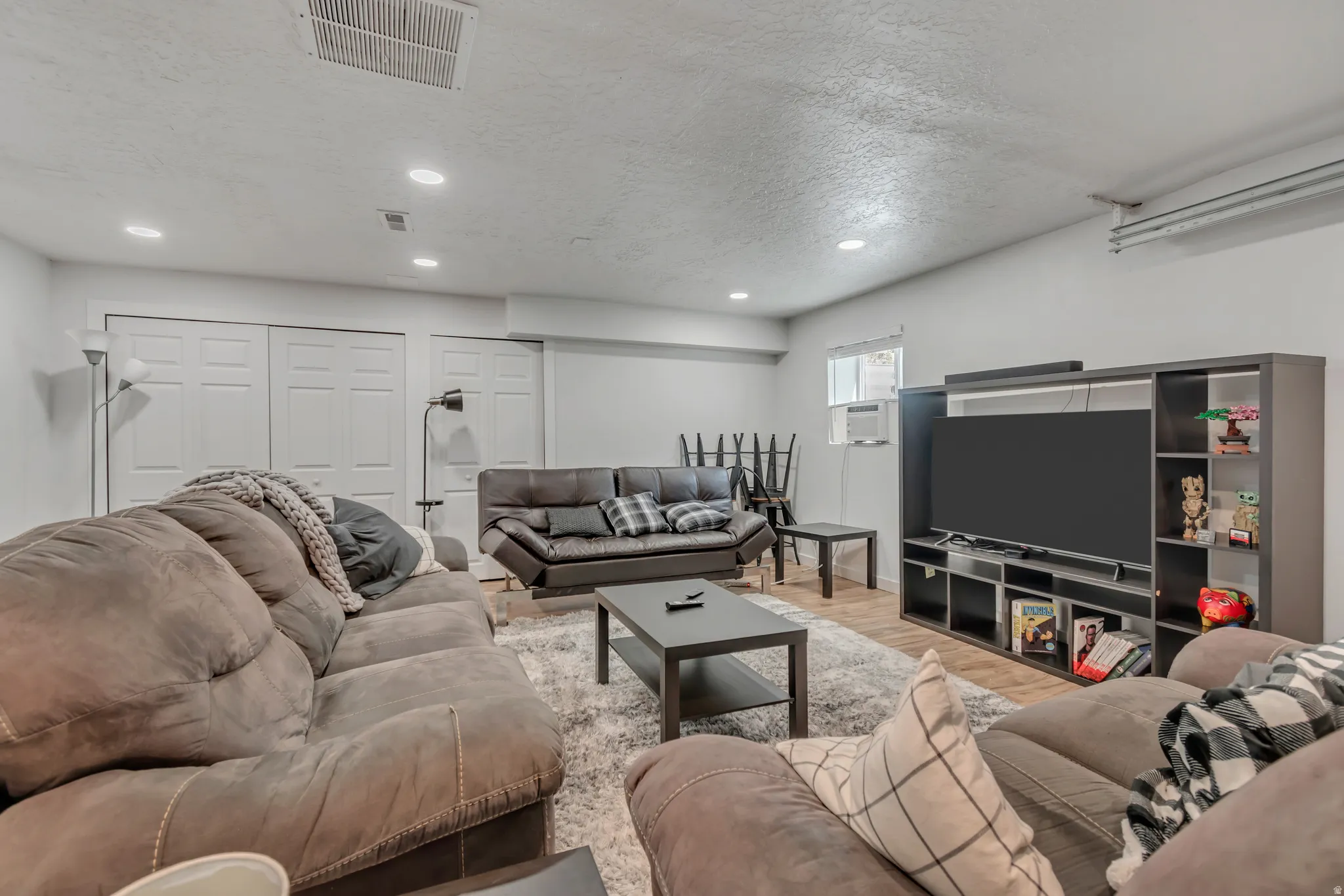 Living room with a textured ceiling, wood finished floors, recessed lighting, and cooling unit