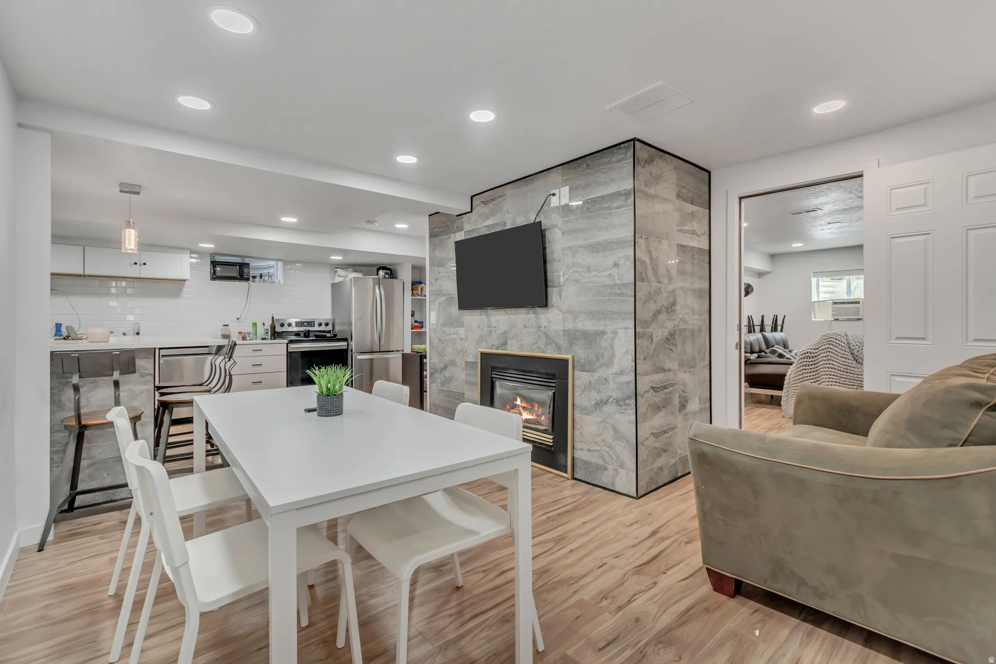 Dining area featuring light wood-style floors, a large fireplace, and recessed lighting