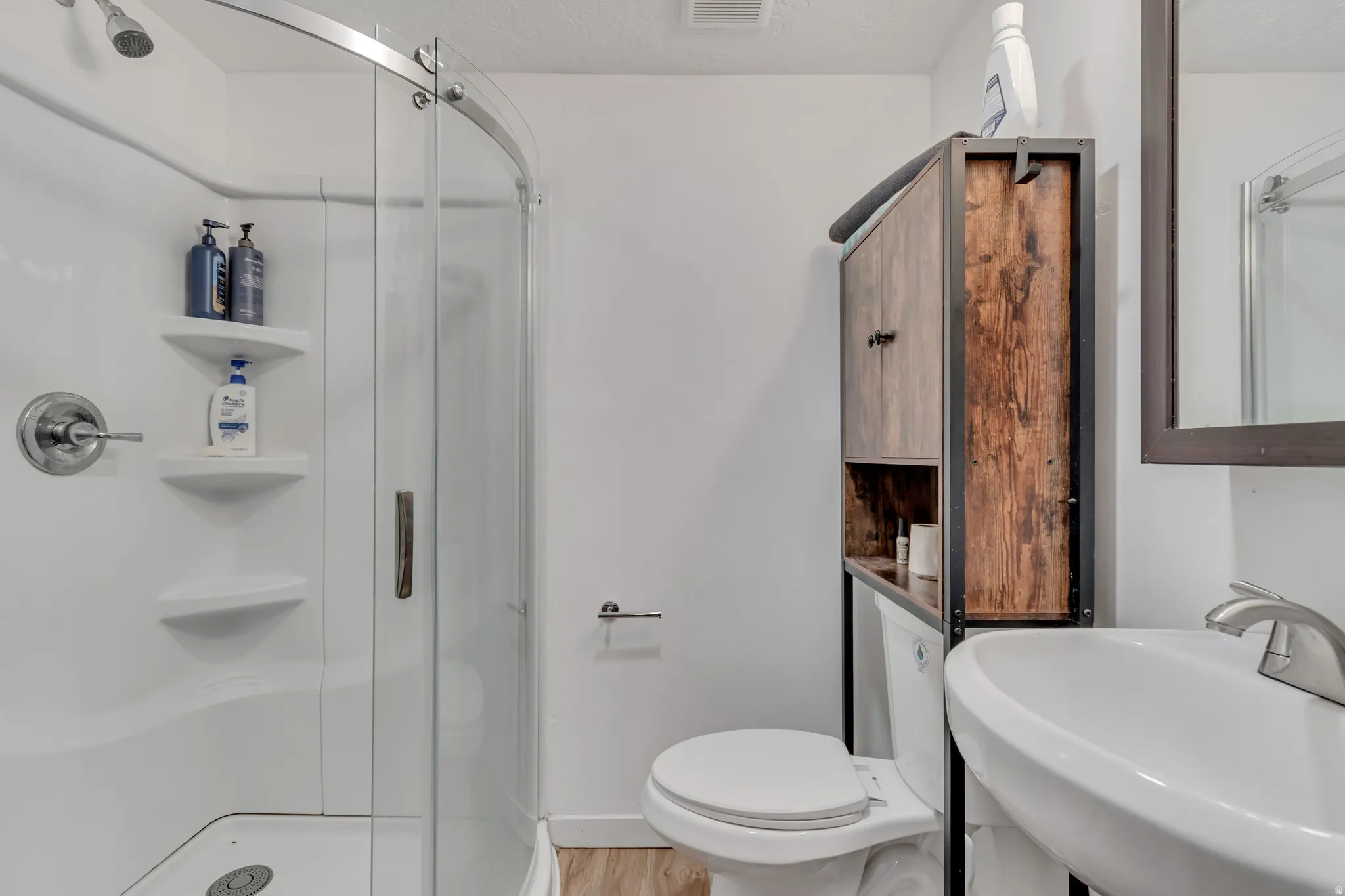 Full bathroom with a stall shower and light wood finished floors