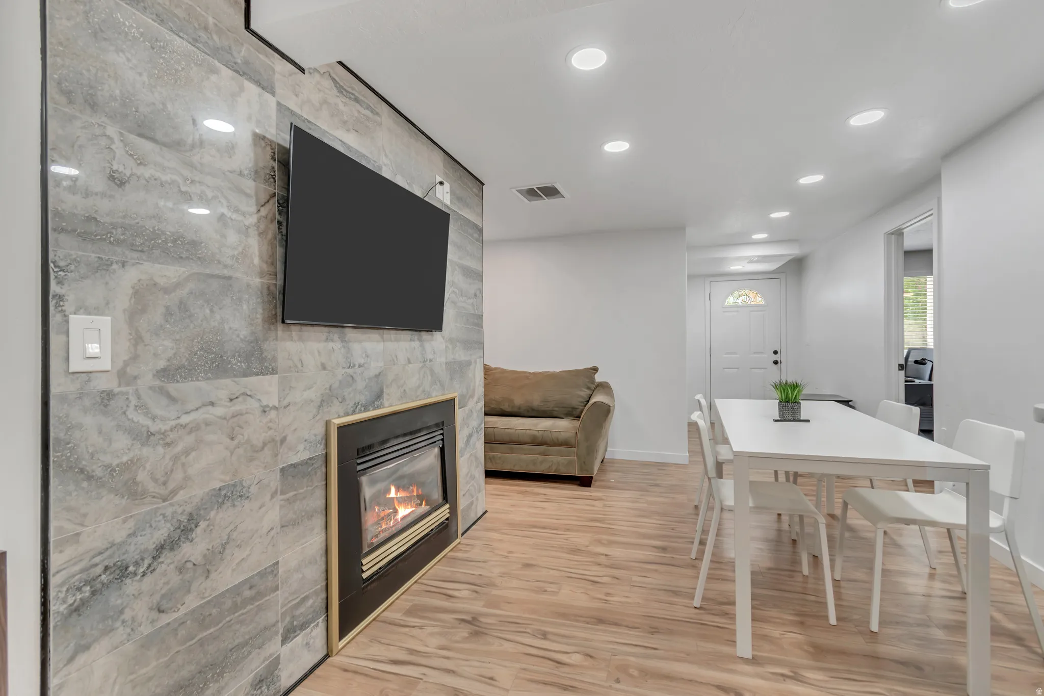 Dining area featuring recessed lighting, light wood-style floors, and a tiled fireplace