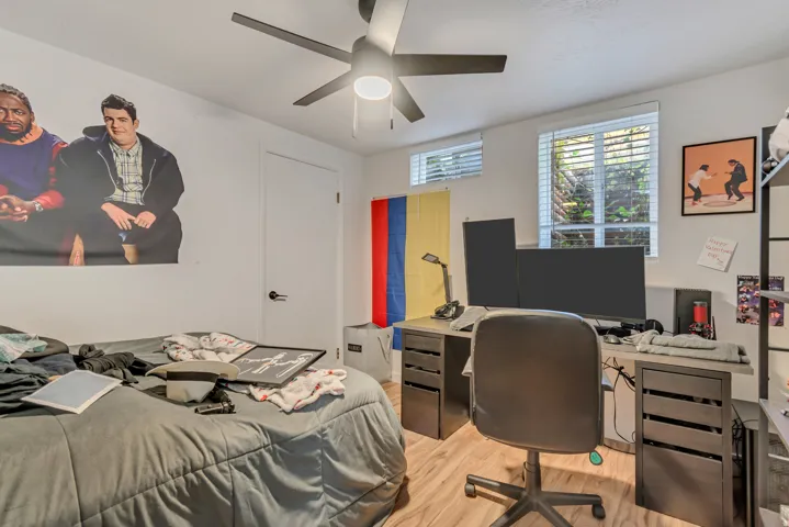 Bedroom with an office area, light wood-type flooring, and a ceiling fan