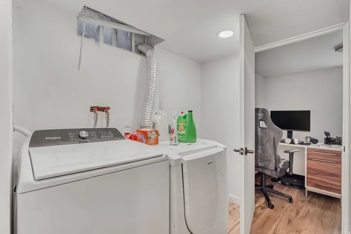 Laundry room featuring light wood-type flooring, independent washer and dryer, and a desk