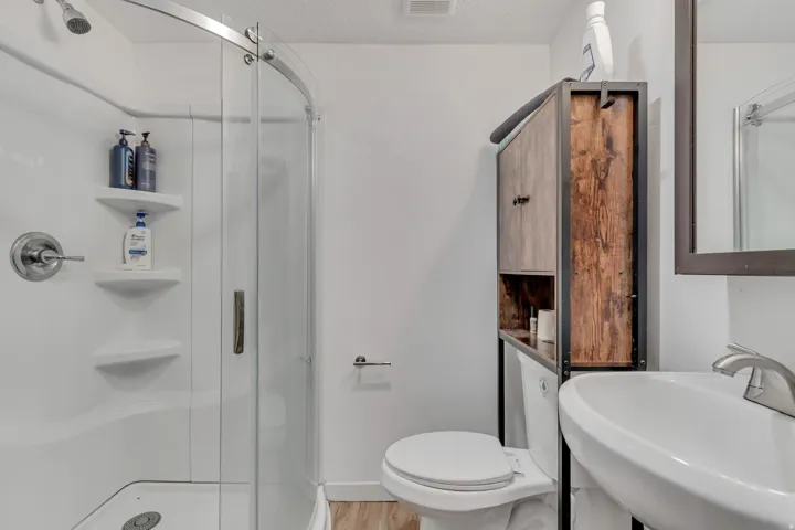 Full bathroom with a stall shower and light wood finished floors