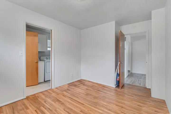 Empty room with light wood-type flooring, a textured ceiling, and washer and dryer