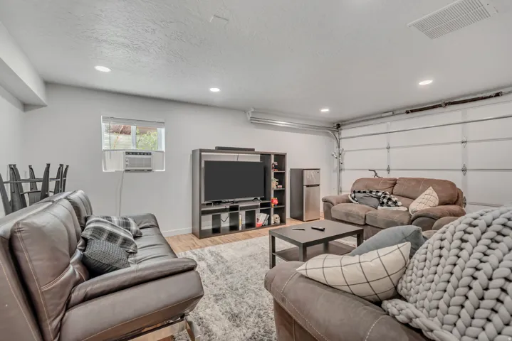 Living room with a garage, light wood-type flooring, recessed lighting, a textured ceiling, and cooling unit