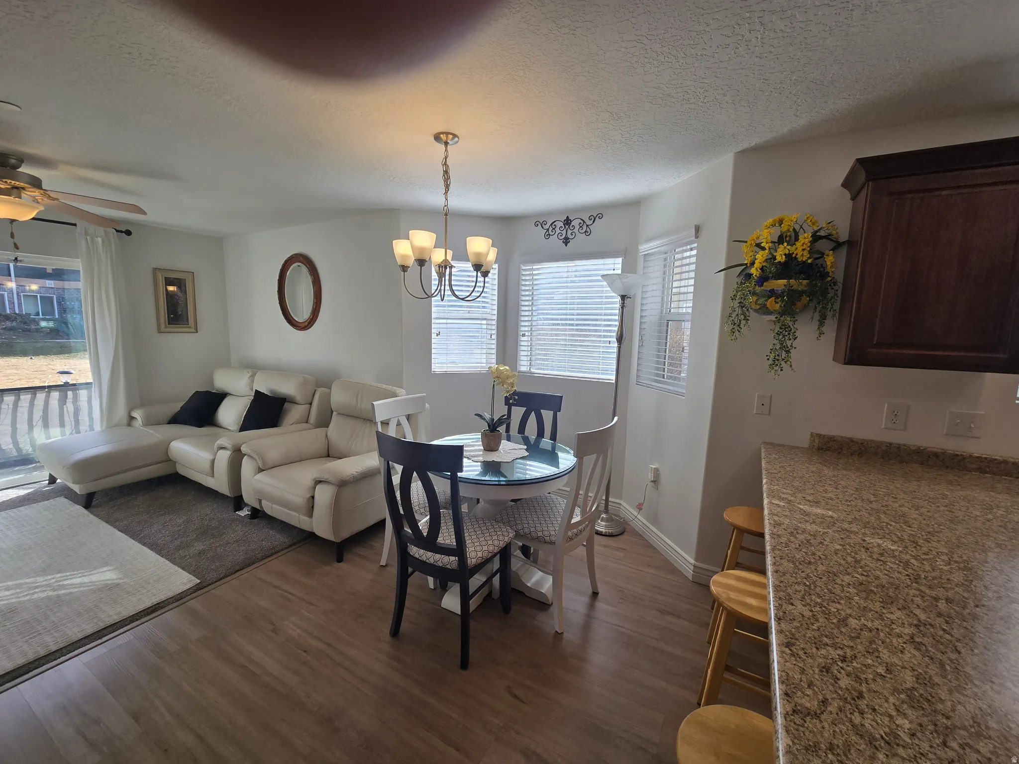 Dining room with a ceiling fan, suspended lighting, dark wood finished floors, and a textured ceiling