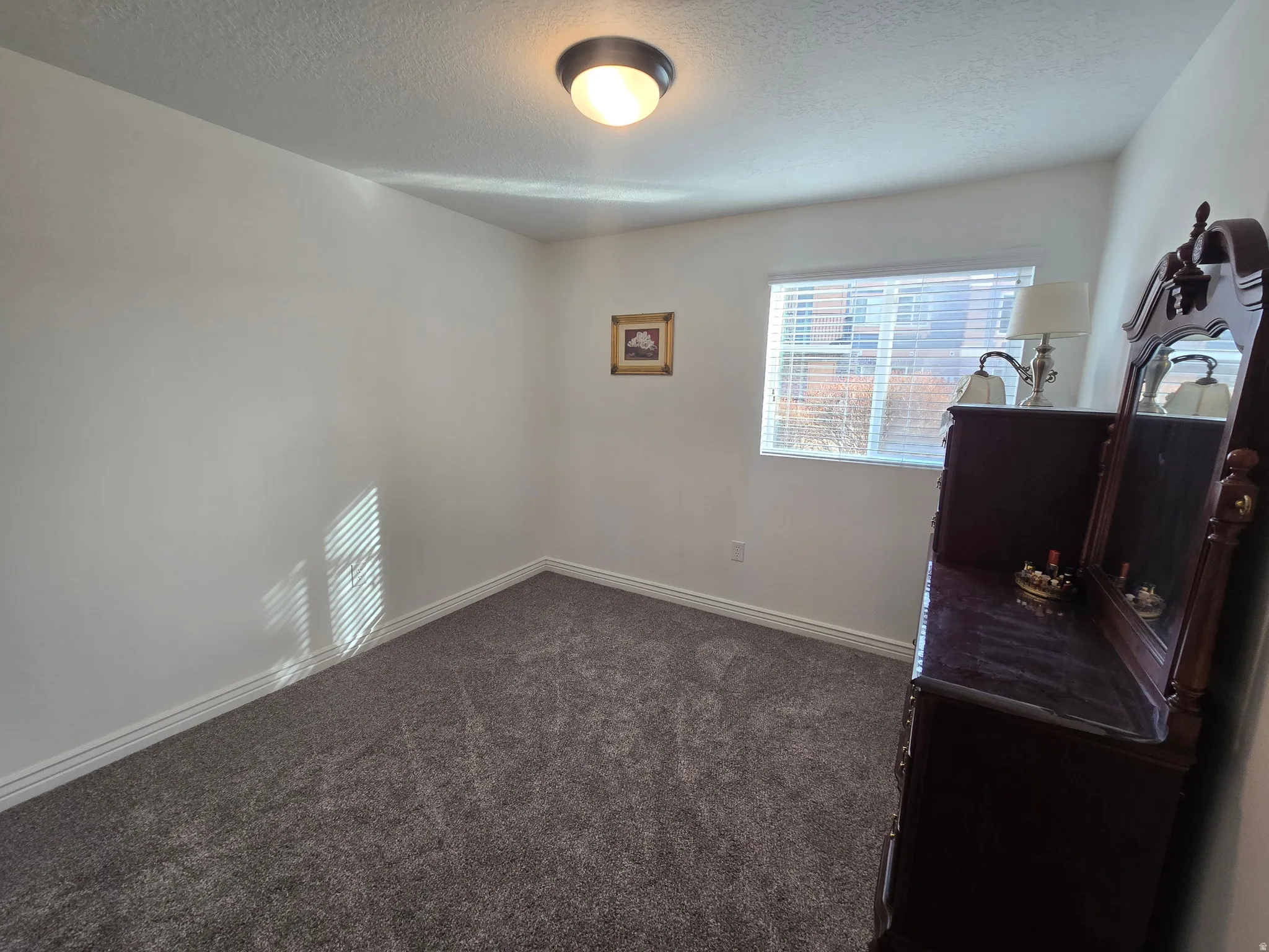 Bedroom with dark colored carpet and a textured ceiling